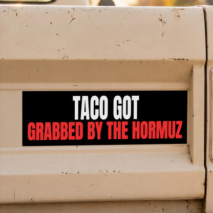 Black sticker on a tan surface reads &amp;quot;TACO GOT GRABBED BY THE HORMUZ&amp;quot;.