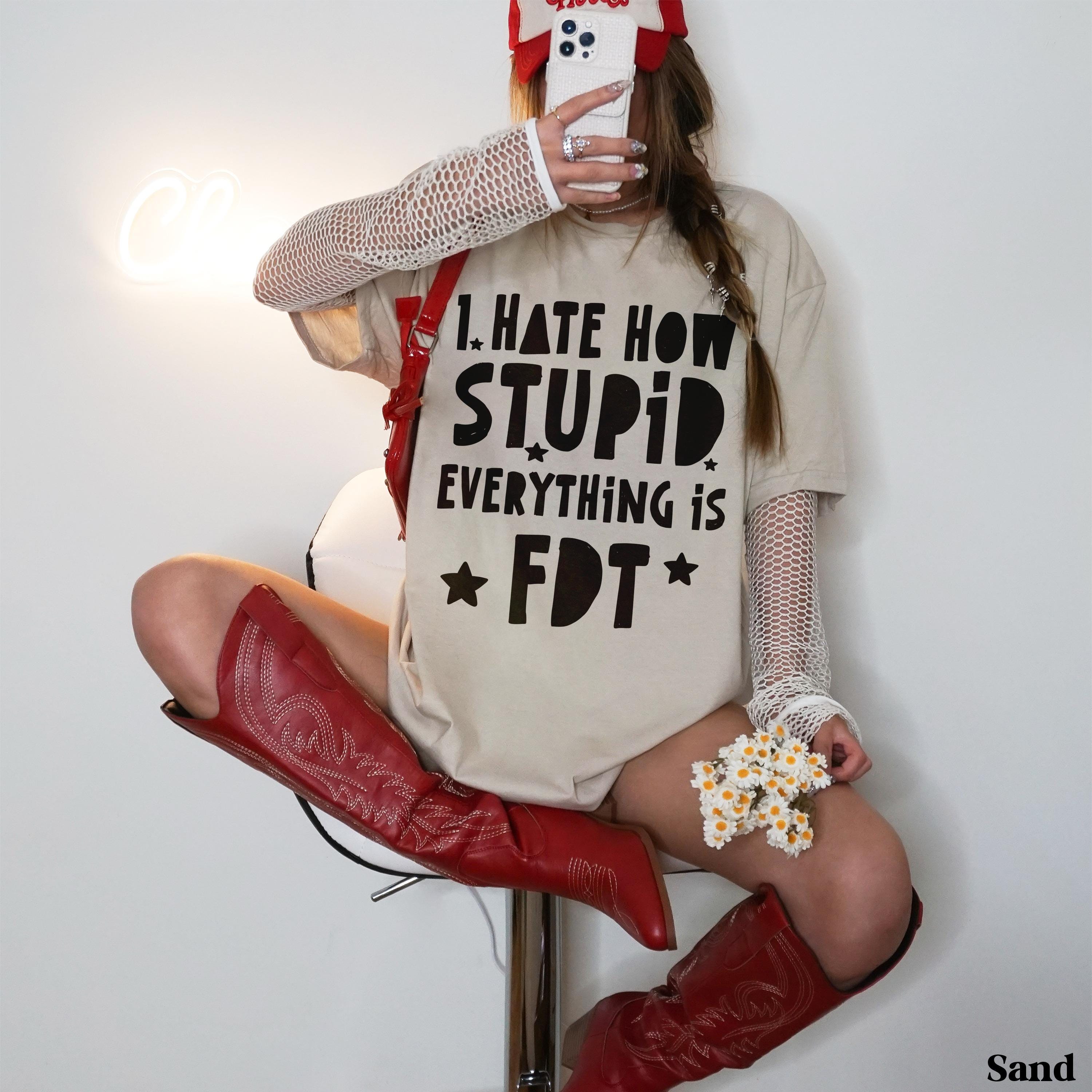 Woman wearing tan graphic tee with &amp;quot;I HATE HOW EVERYTHING IS FDT&amp;quot; text and red cowboy boots.