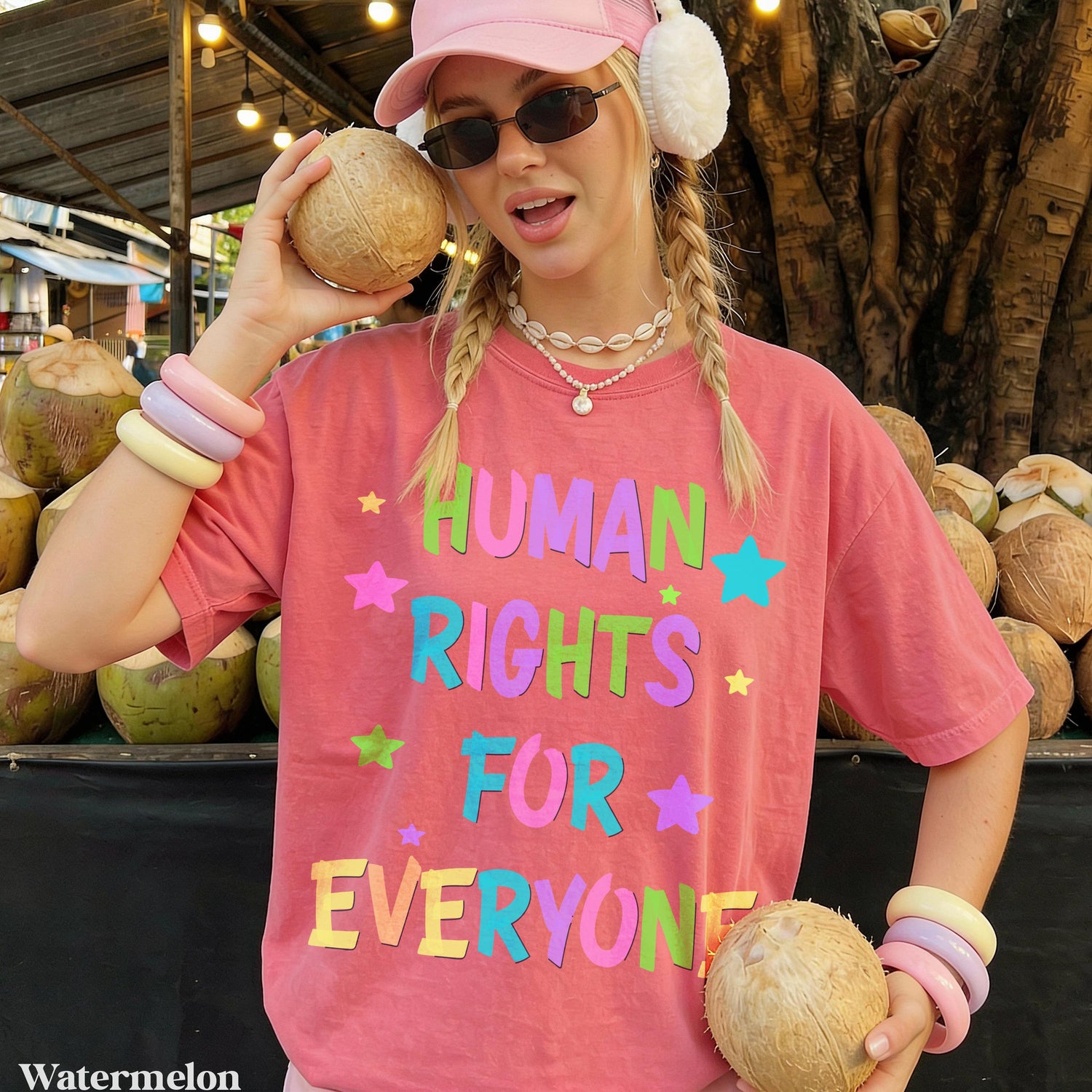 Woman wearing pink t-shirt with &amp;quot;HUMAN RIGHTS FOR EVERYONE&amp;quot; text holding coconuts.