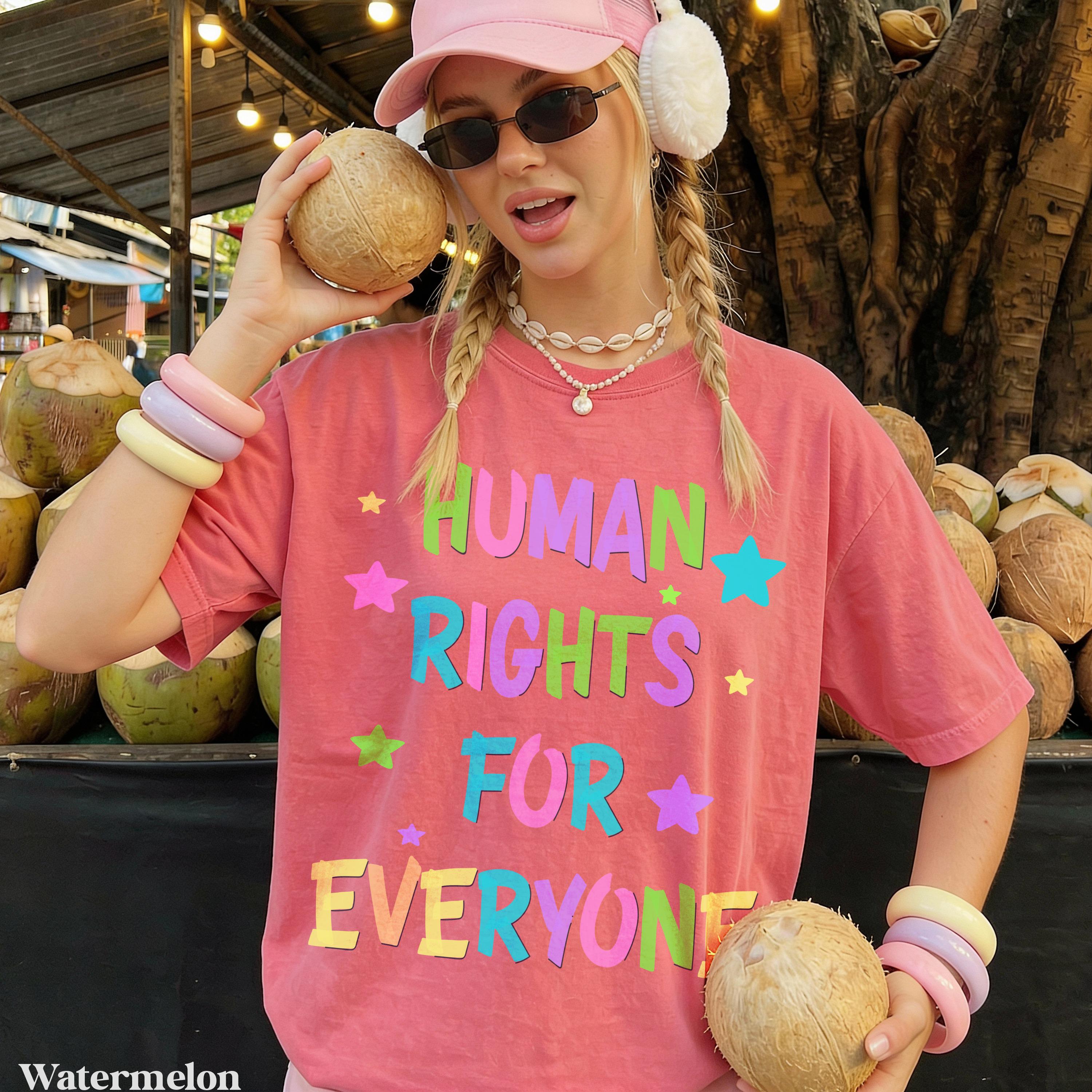 Woman wearing pink t-shirt with &amp;quot;HUMAN RIGHTS FOR EVERYONE&amp;quot; text holding coconuts.