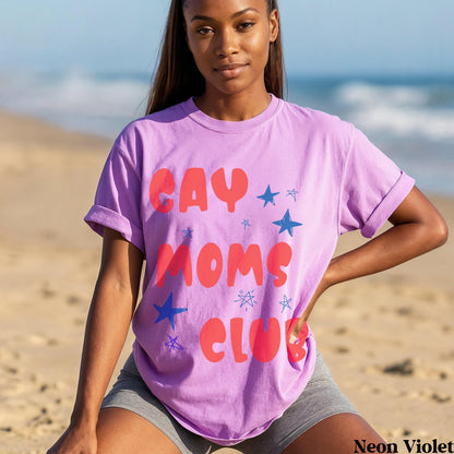 Woman wearing a purple t-shirt with &amp;quot;GAY MOMS CLUB&amp;quot; in red letters and blue stars.