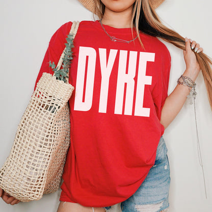 Red t-shirt with &amp;quot;DYKE&amp;quot; in white lettering, worn by a person holding a woven bag.