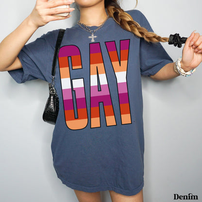 Woman in charcoal t-shirt with &amp;quot;GAY&amp;quot; in rainbow stripes, holding purse and phone.
