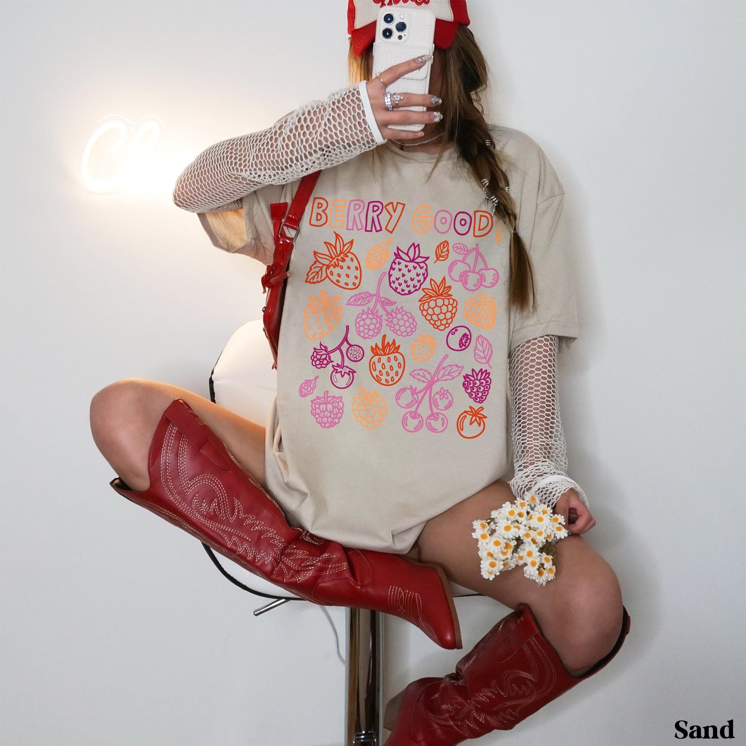 Woman in beige t-shirt with &amp;quot;Berry Good&amp;quot; text and berry illustrations, wearing red boots.
