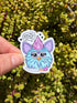 May include: A sticker featuring a cartoon creature with blue fur, large eyes, and a pink tuft of hair. The creature is holding a knife and has the text "what the fuck did you just say?" in a speech bubble.