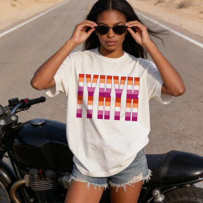 Woman wearing cream t-shirt with colorful LGBTQIA+ stripes and text.