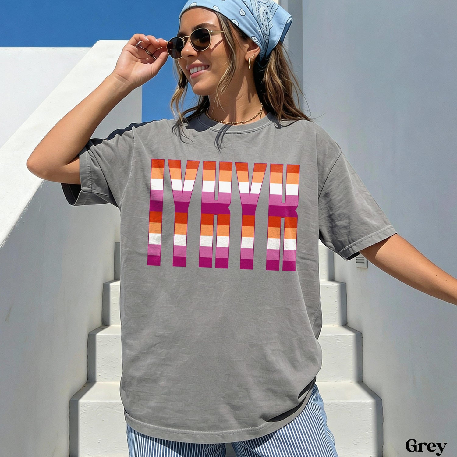 Woman wearing a grey t-shirt with lesbian pride flag stripes spelling &amp;quot;GIRL&amp;quot;.