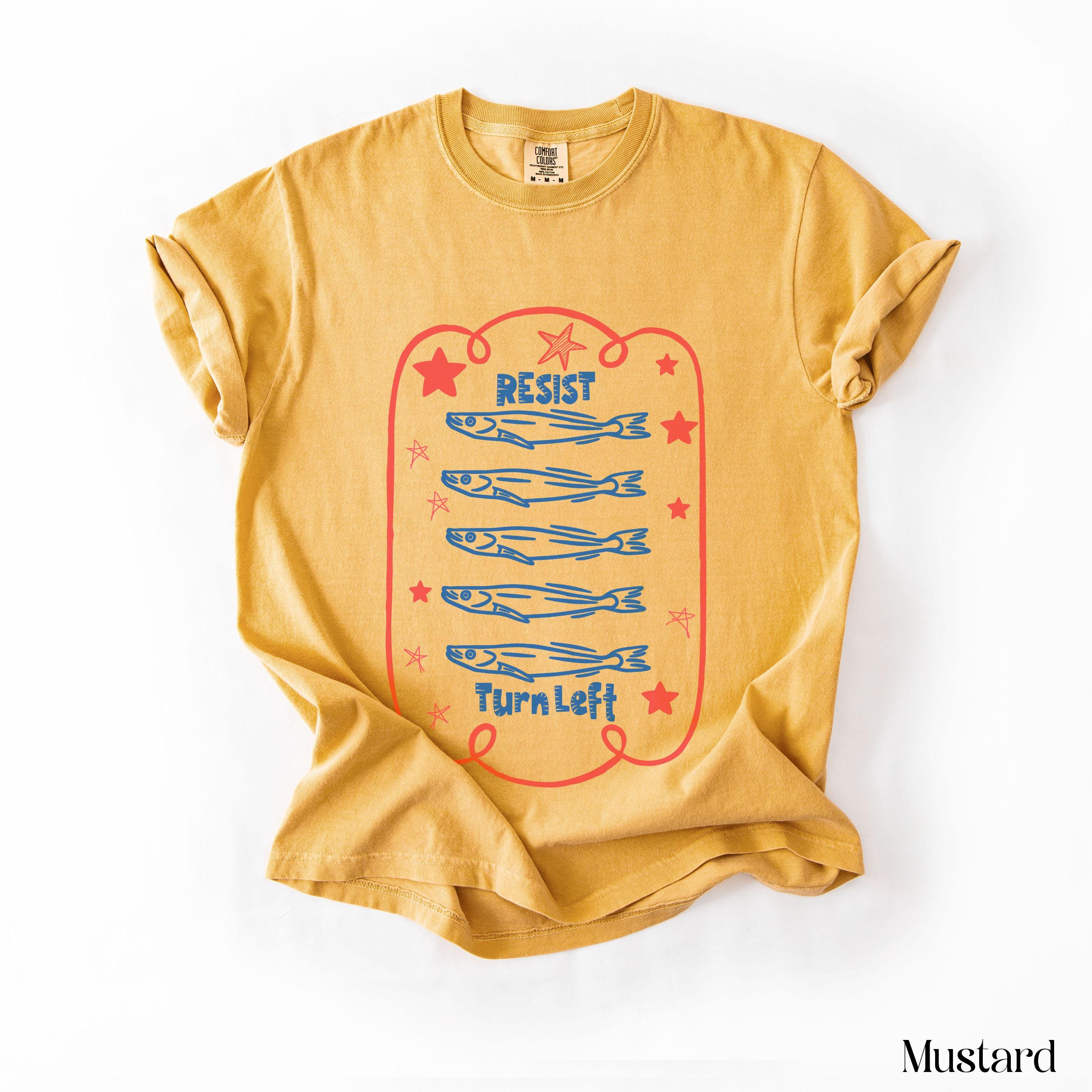 Mustard t-shirt with red text and blue fish graphic.