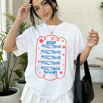 White t-shirt with blue fish graphic and &amp;quot;RESIST&amp;quot; and &amp;quot;TURN LEFT&amp;quot; text.