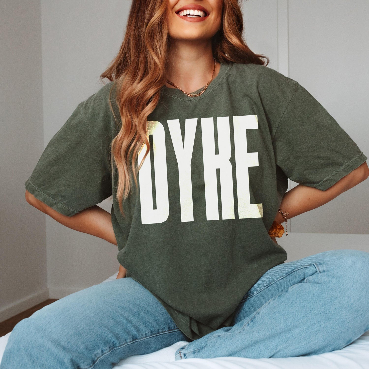 Dark green t-shirt with &amp;quot;DYKE&amp;quot; in large white letters, worn by a smiling person.