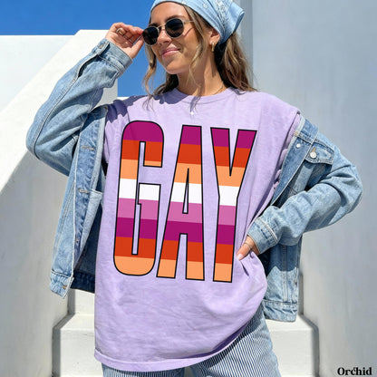 Woman wearing a lavender t-shirt with &amp;quot;GAY&amp;quot; in rainbow stripes.
