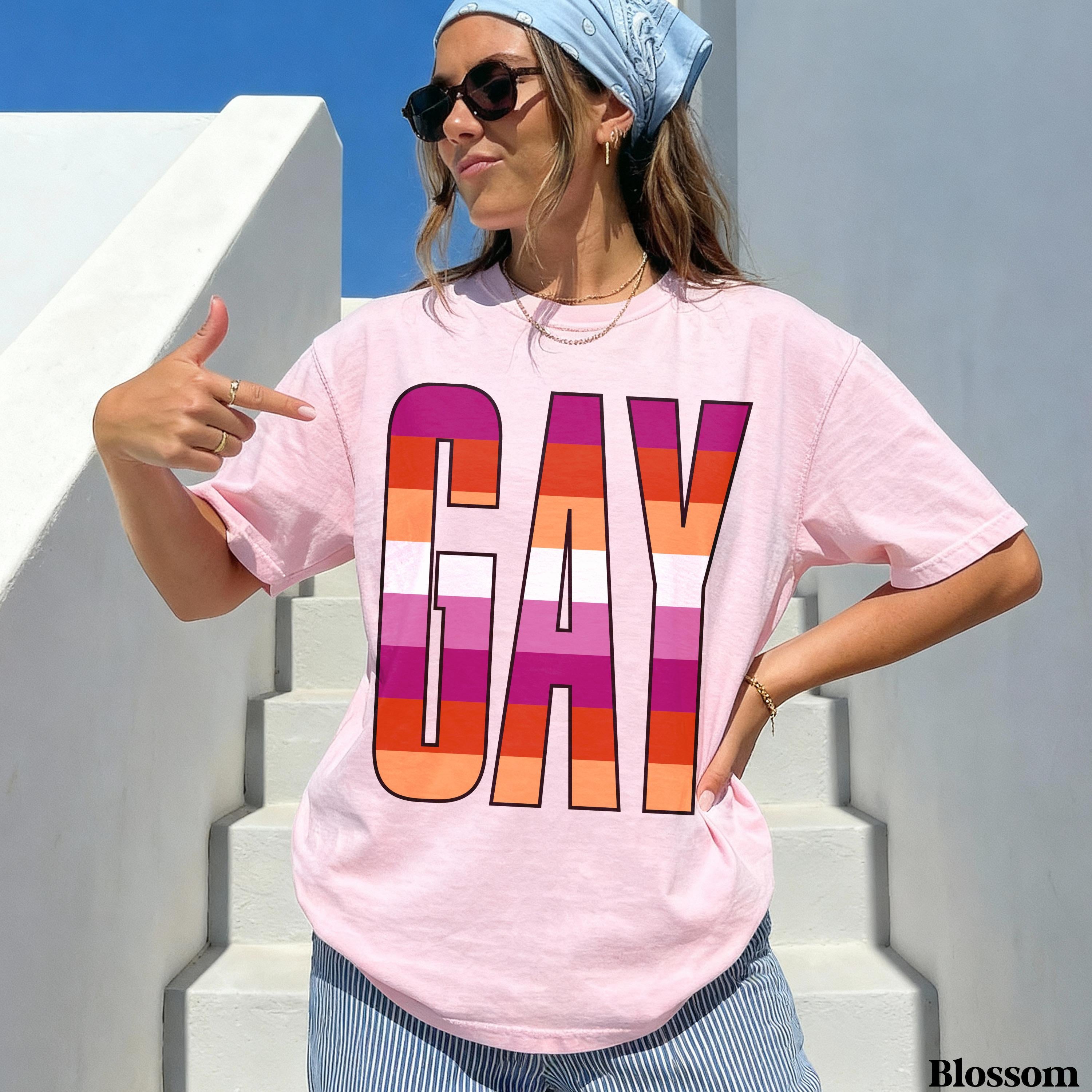 Pink t-shirt with &amp;quot;GAY&amp;quot; in rainbow stripes, woman pointing at text.