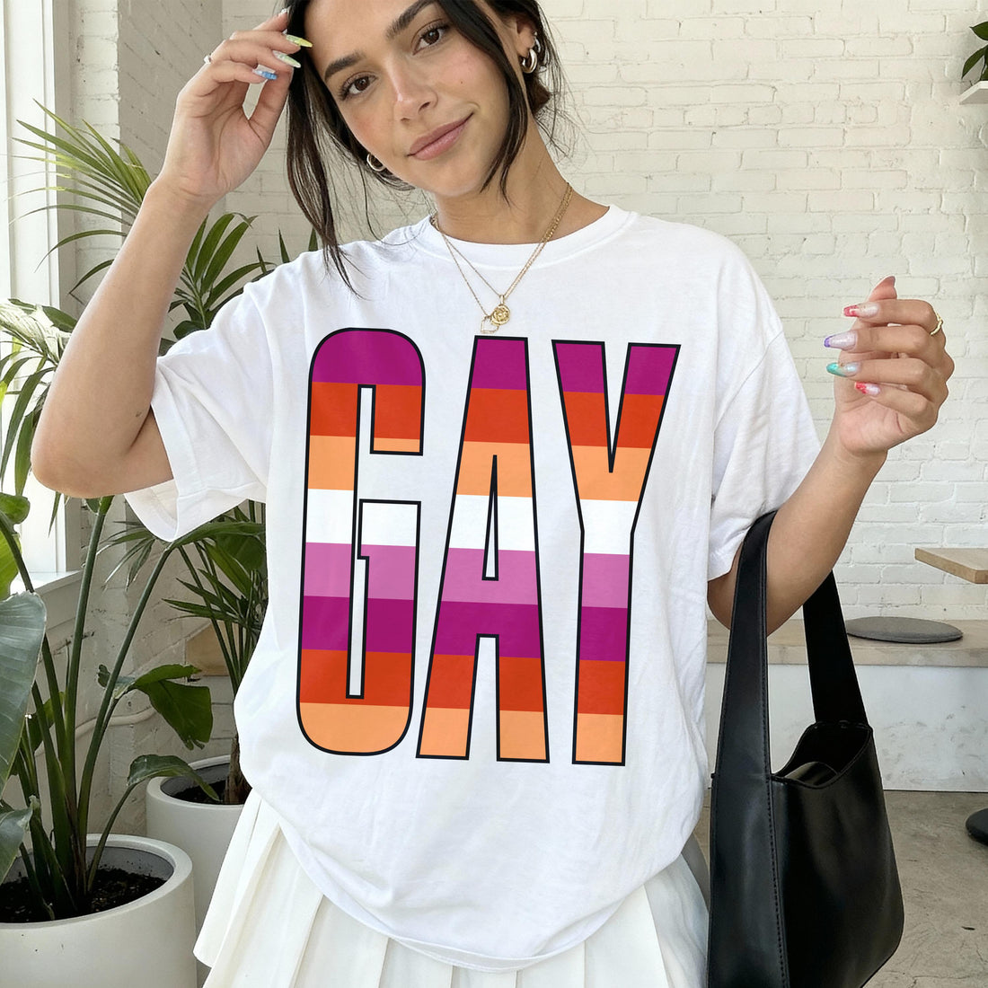 Woman in white t-shirt with rainbow &amp;quot;GAY&amp;quot; graphic and black handbag.