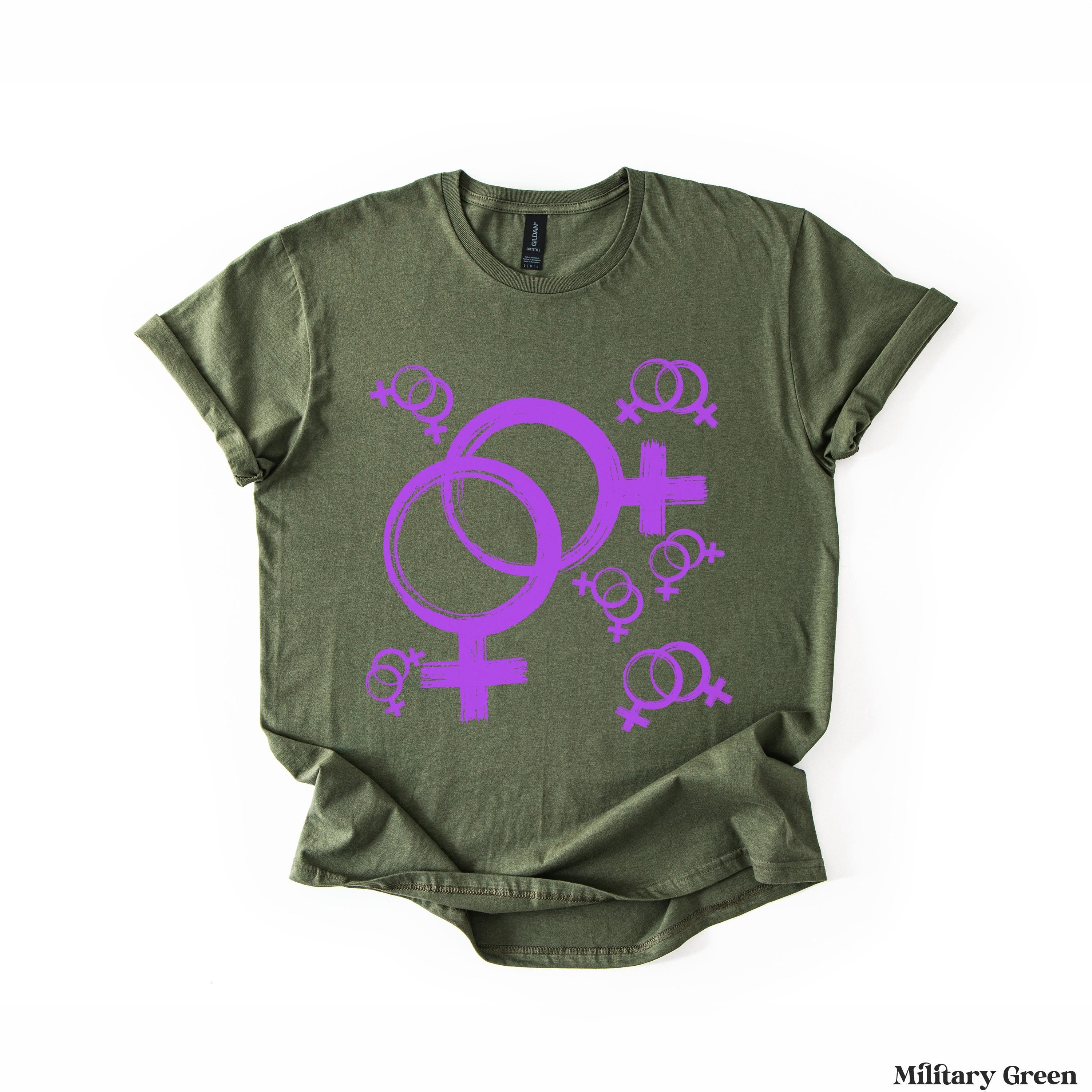 Olive green t-shirt with purple Venus symbols and smaller symbols scattered.