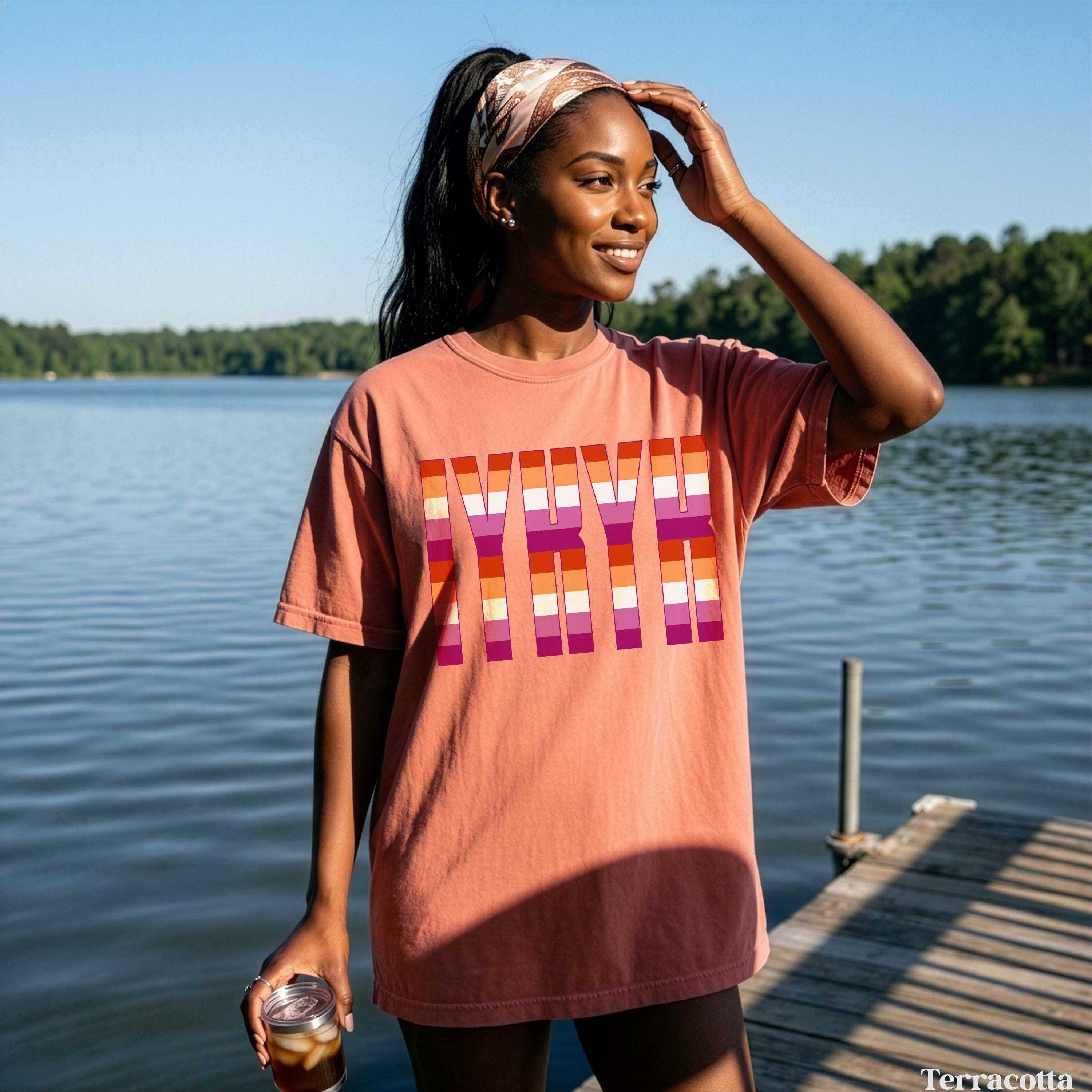 Woman in oversized terracotta t-shirt with stacked &amp;quot;LOVE&amp;quot; in pride flag colors.