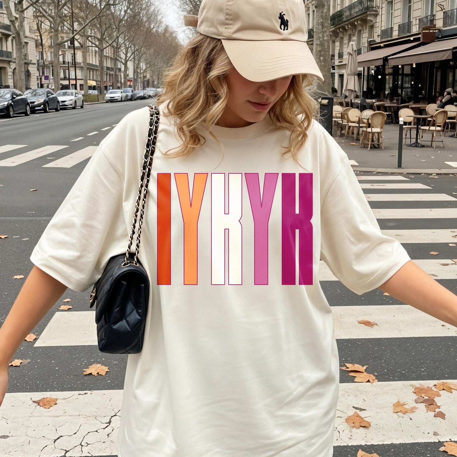 Woman wearing cream t-shirt with pink, orange, and purple &amp;quot;IYKYK&amp;quot; graphic.