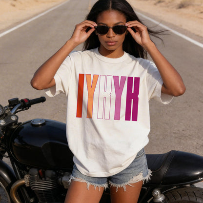 Woman wearing a cream t-shirt with &amp;quot;IYKYK&amp;quot; in colorful letters.