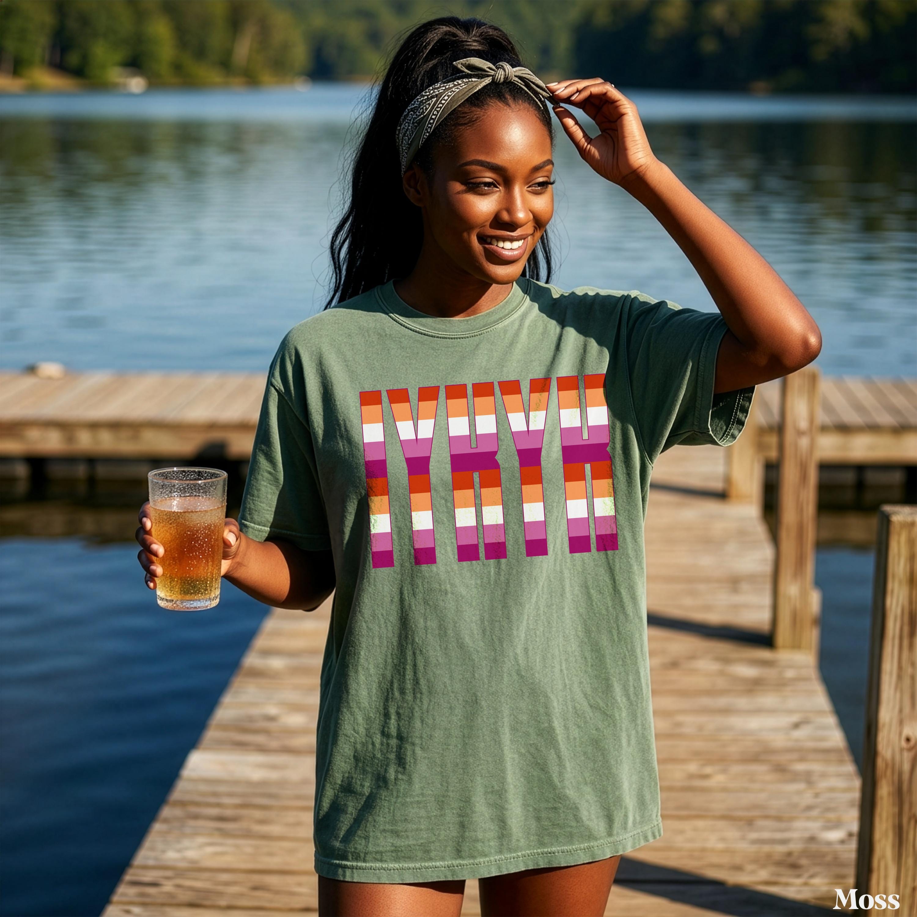 Woman in olive green t-shirt with rainbow stripes spelling &amp;quot;MYVR&amp;quot; holding a beer.