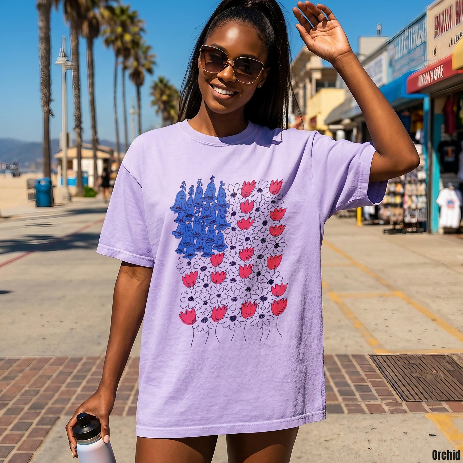 Purple t-shirt with abstract US flag design featuring red flowers and blue figures.