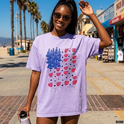 Purple t-shirt with abstract US flag design featuring red flowers and blue figures.