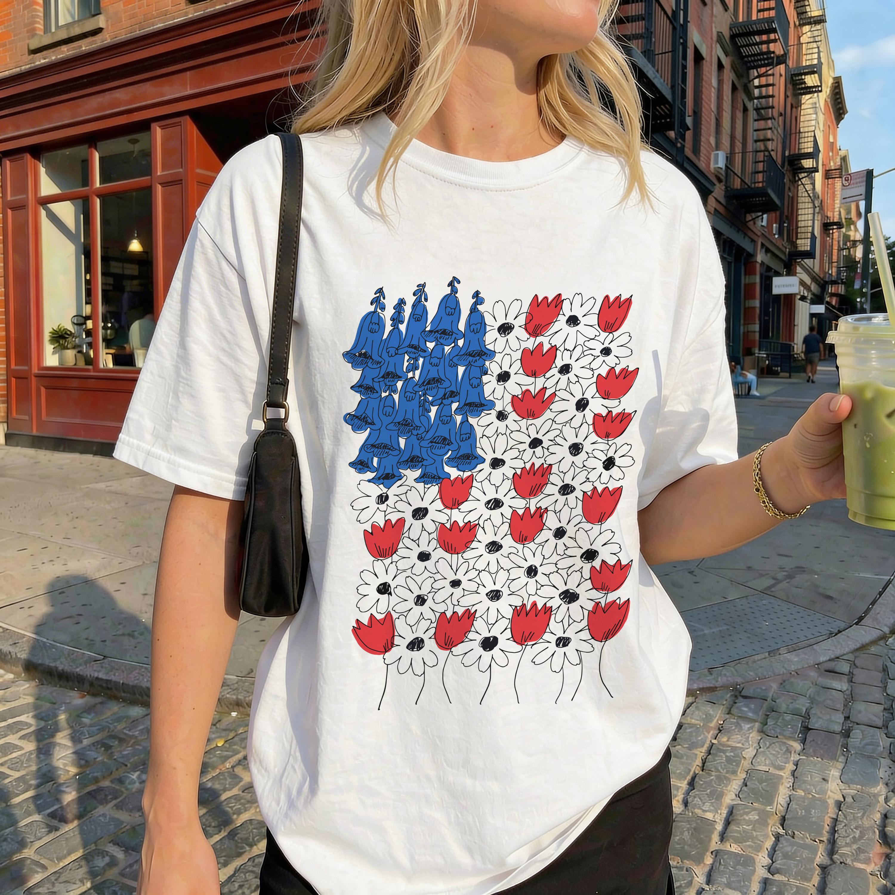 White t-shirt with red and white flowers and blue abstract shapes.