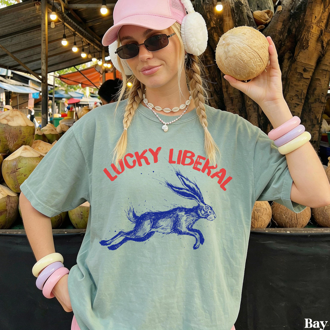 Woman in light green &amp;quot;Lucky Liberal&amp;quot; t-shirt holding a coconut.