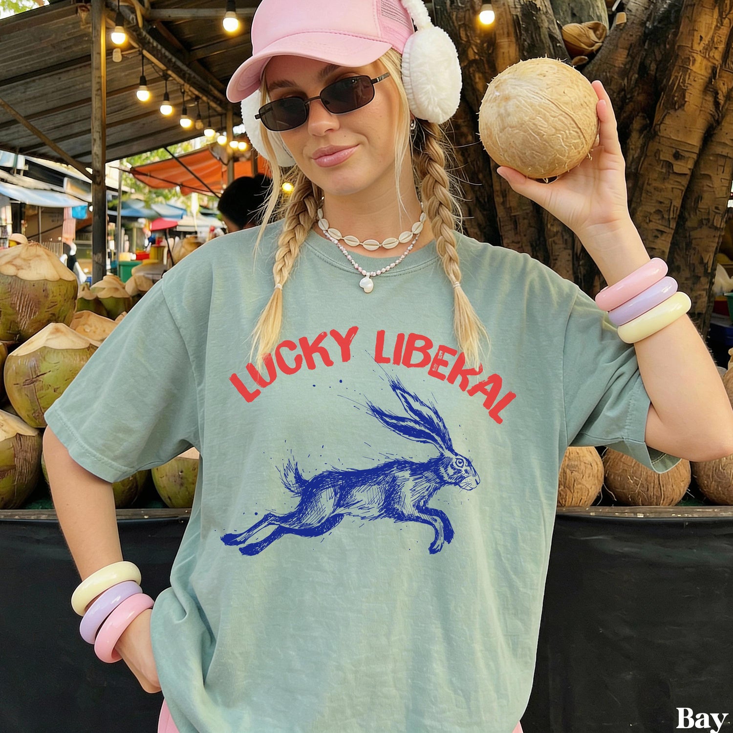 Woman in light green &amp;quot;Lucky Liberal&amp;quot; t-shirt holding a coconut.