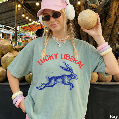 Woman in light green &amp;quot;Lucky Liberal&amp;quot; t-shirt holding a coconut.