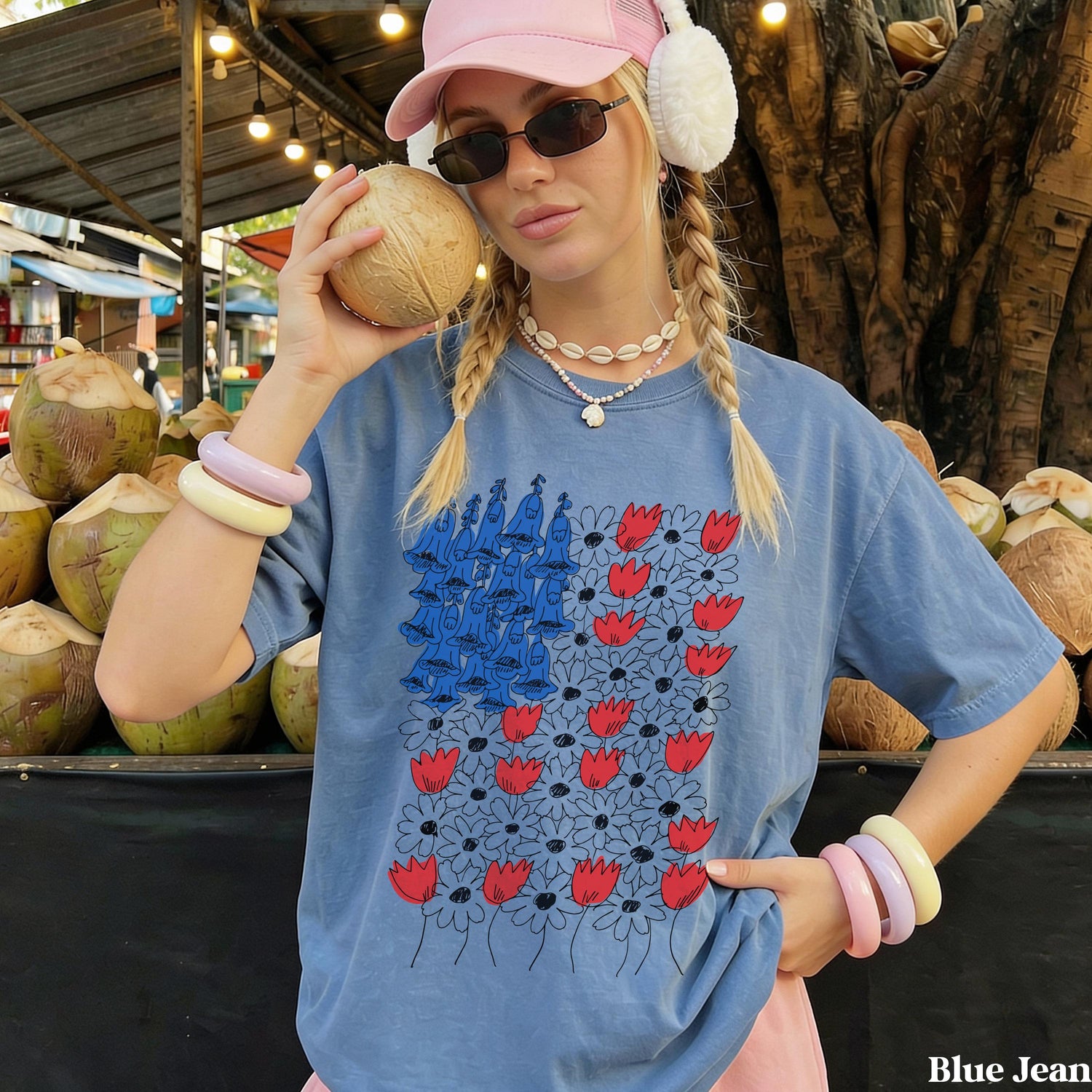 Woman in blue t-shirt with red flowers and blue figures, holding a coconut.