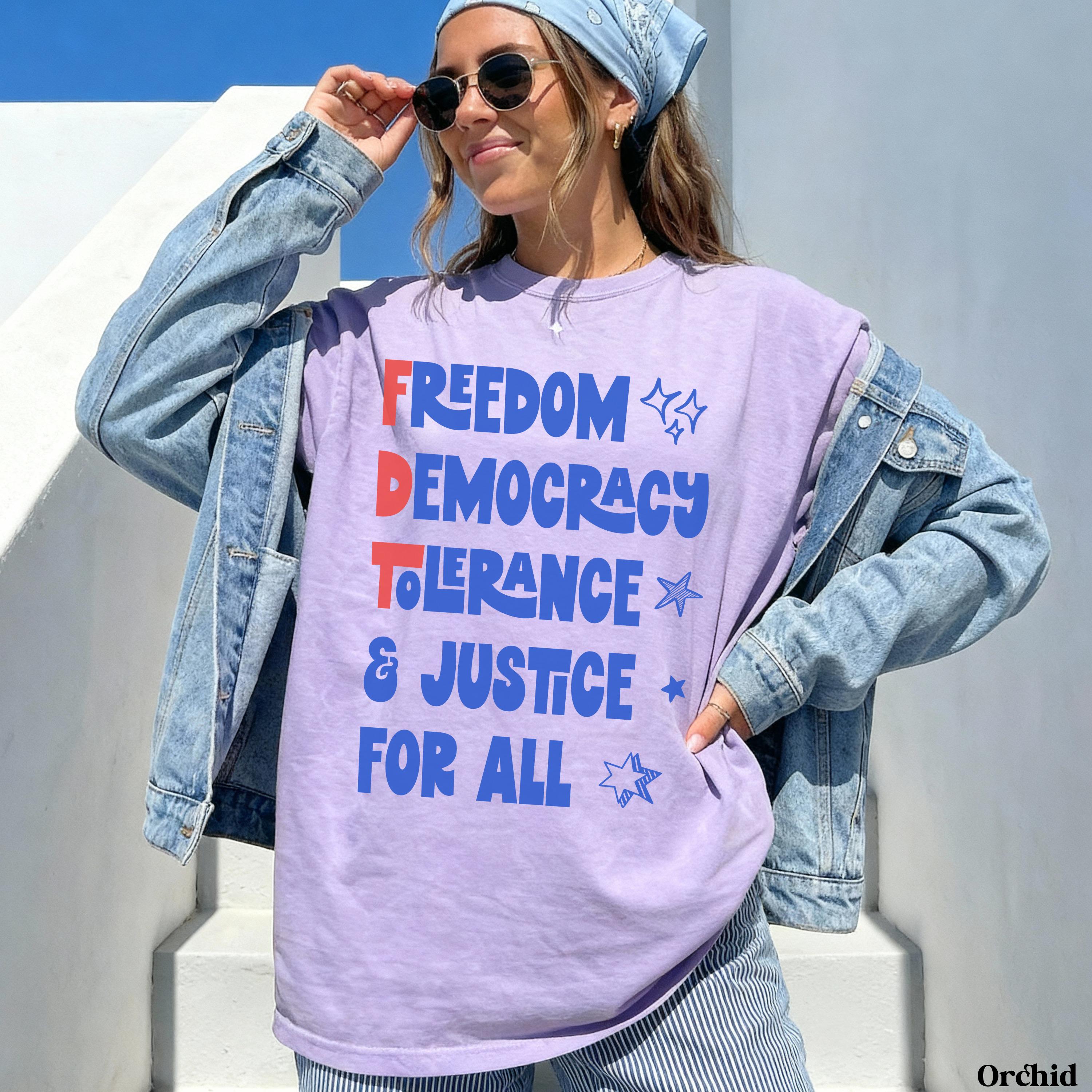 Woman wearing a purple t-shirt with &amp;quot;FREEDOM DEMOCRACY TOLERANCE JUSTICE FOR ALL&amp;quot; text.
