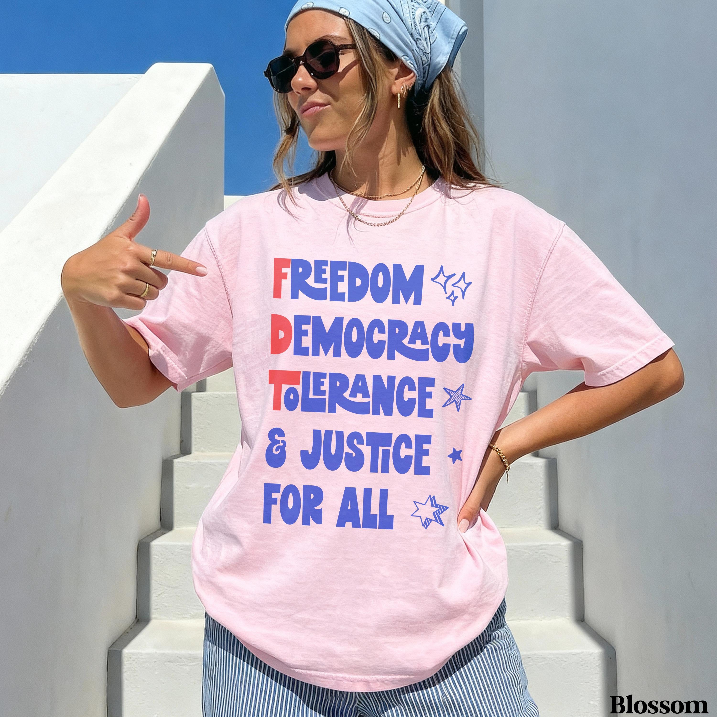 Pink t-shirt with &amp;quot;FREEDOM DEMOCRACY TOLERANCE &amp; JUSTICE FOR ALL&amp;quot; text.