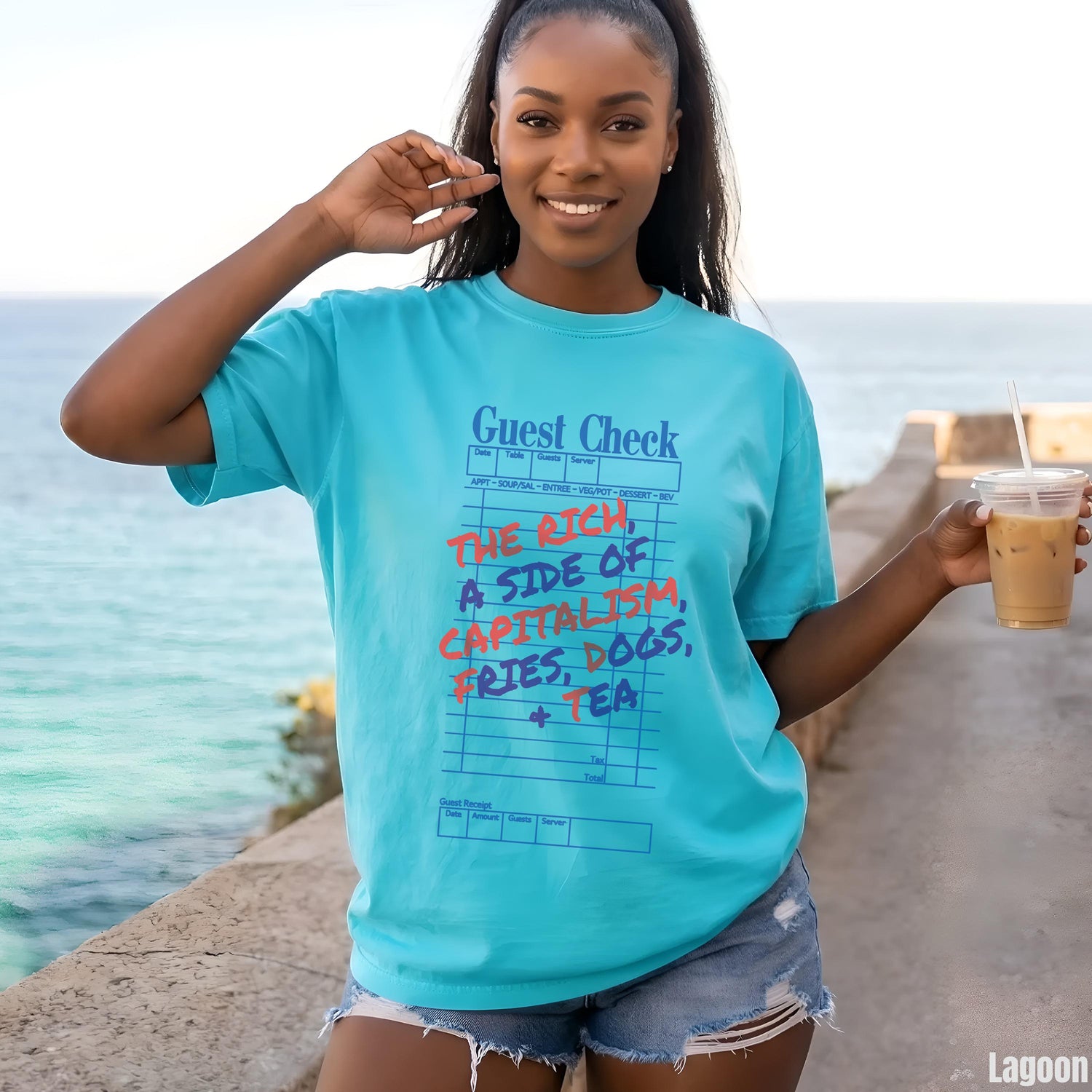 Woman wearing a turquoise t-shirt with &amp;quot;The Rich, a side of capitalism, fries, dogs, tea&amp;quot; printed on it.