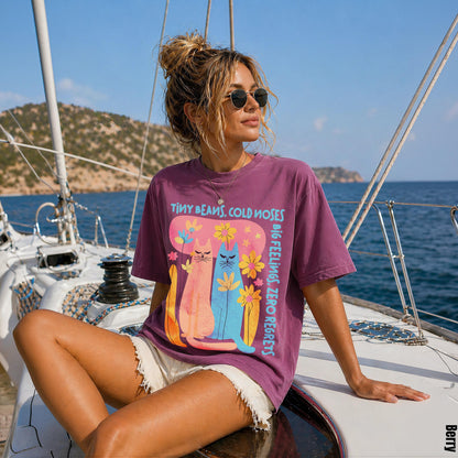 Woman wearing purple t-shirt with &amp;quot;Tiny Beans, Cold Noses&amp;quot; cat graphic, on a sailboat.