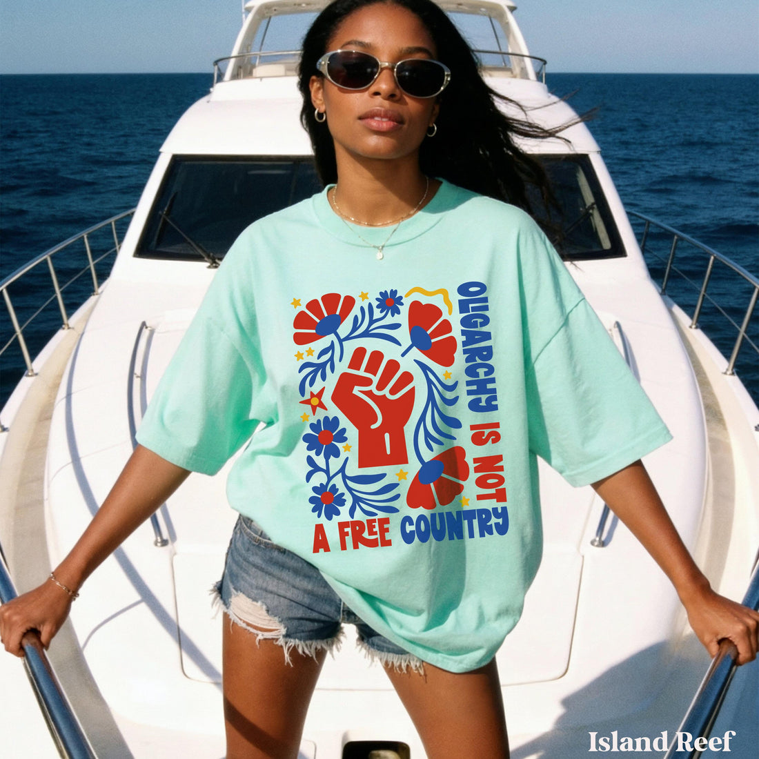 Woman in mint t-shirt with &amp;quot;Oligarchs is not a free country&amp;quot; graphic, standing on a boat.