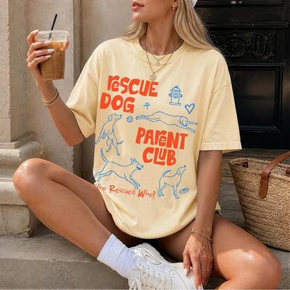 Woman in cream t-shirt with &amp;quot;Rescue Dog Parent Club&amp;quot; graphic, holding iced coffee.