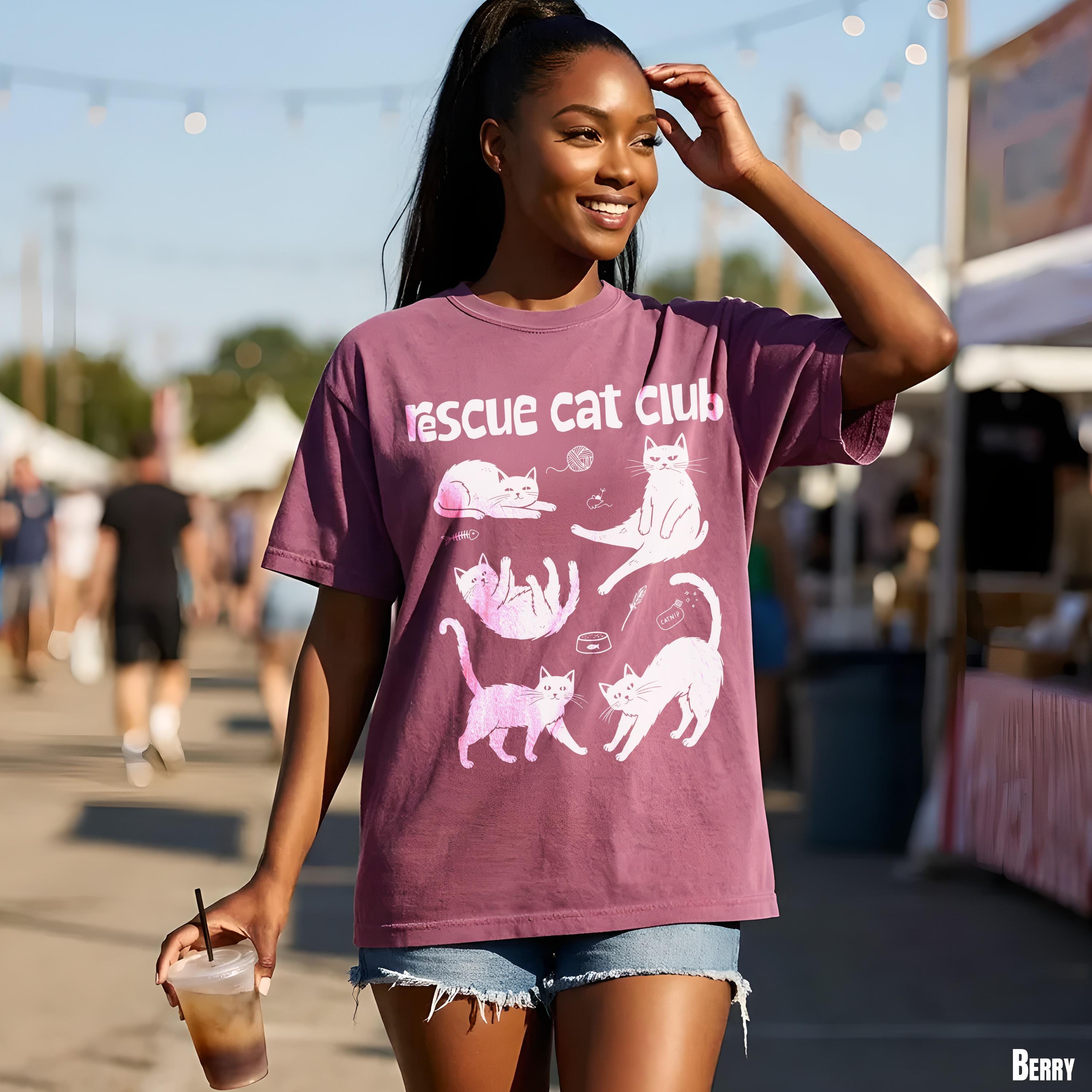 Purple t-shirt with pink cat illustrations and &amp;quot;Rescue Cat Club&amp;quot; text.