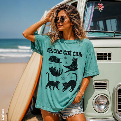 Woman wearing teal &amp;quot;rescue cat club&amp;quot; t-shirt stands by a vintage van.