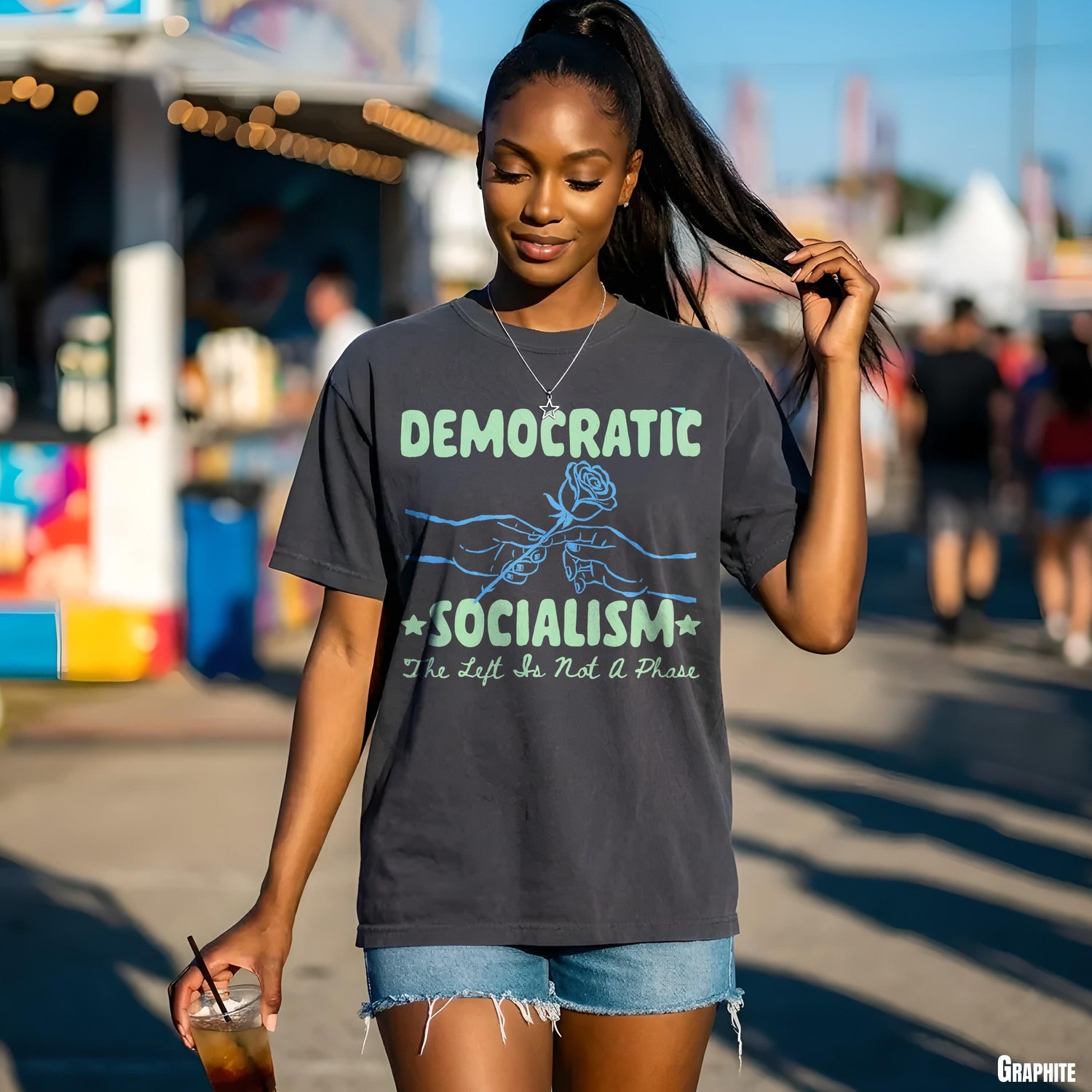 Woman in t-shirt with &amp;quot;Democratic Socialism&amp;quot; text and rose graphic, holding a drink.