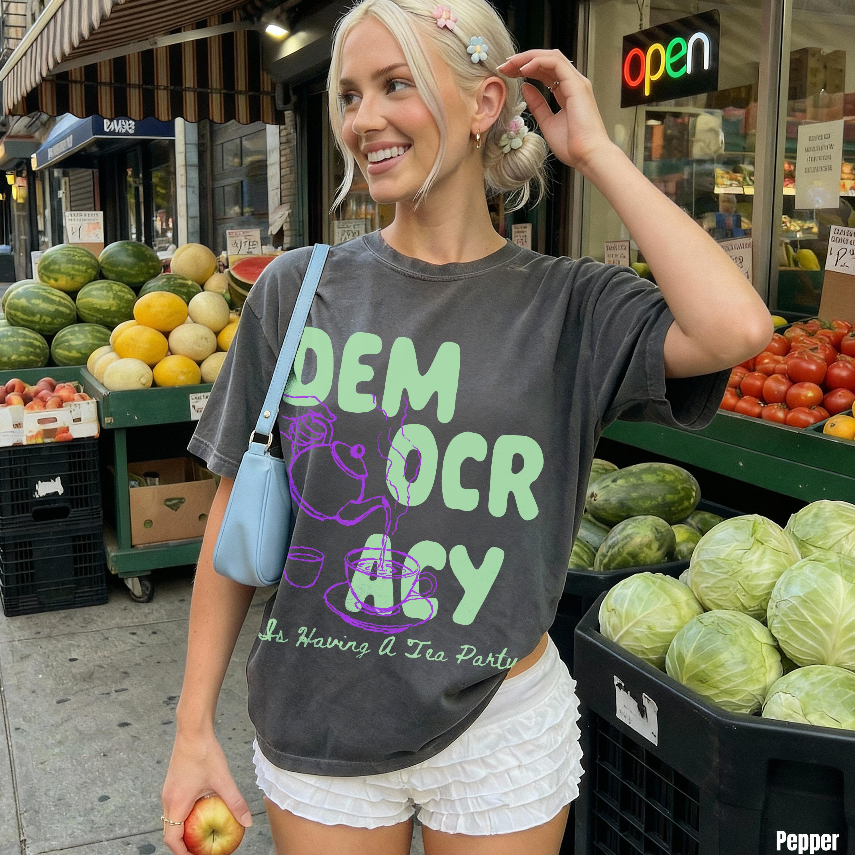 Woman in grey t-shirt with &amp;quot;Democracy is Having A Tea Party&amp;quot; graphic, holding apple.