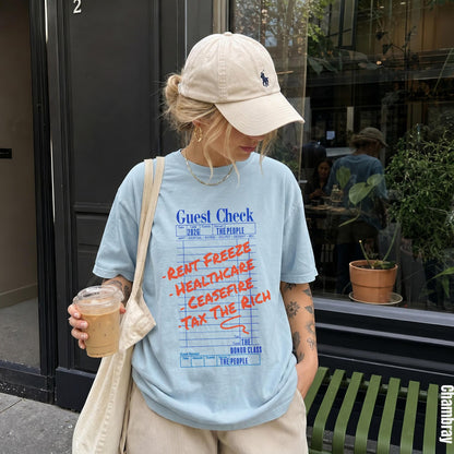 Light blue t-shirt with &amp;quot;Guest Check&amp;quot; text and &amp;quot;Rent Freeze, Healthcare, Ceasefire, Tax the Rich&amp;quot; slogans.