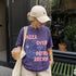 Purple t-shirt with "Pizza Over Patriarchy" graphic and a hand holding coffee.