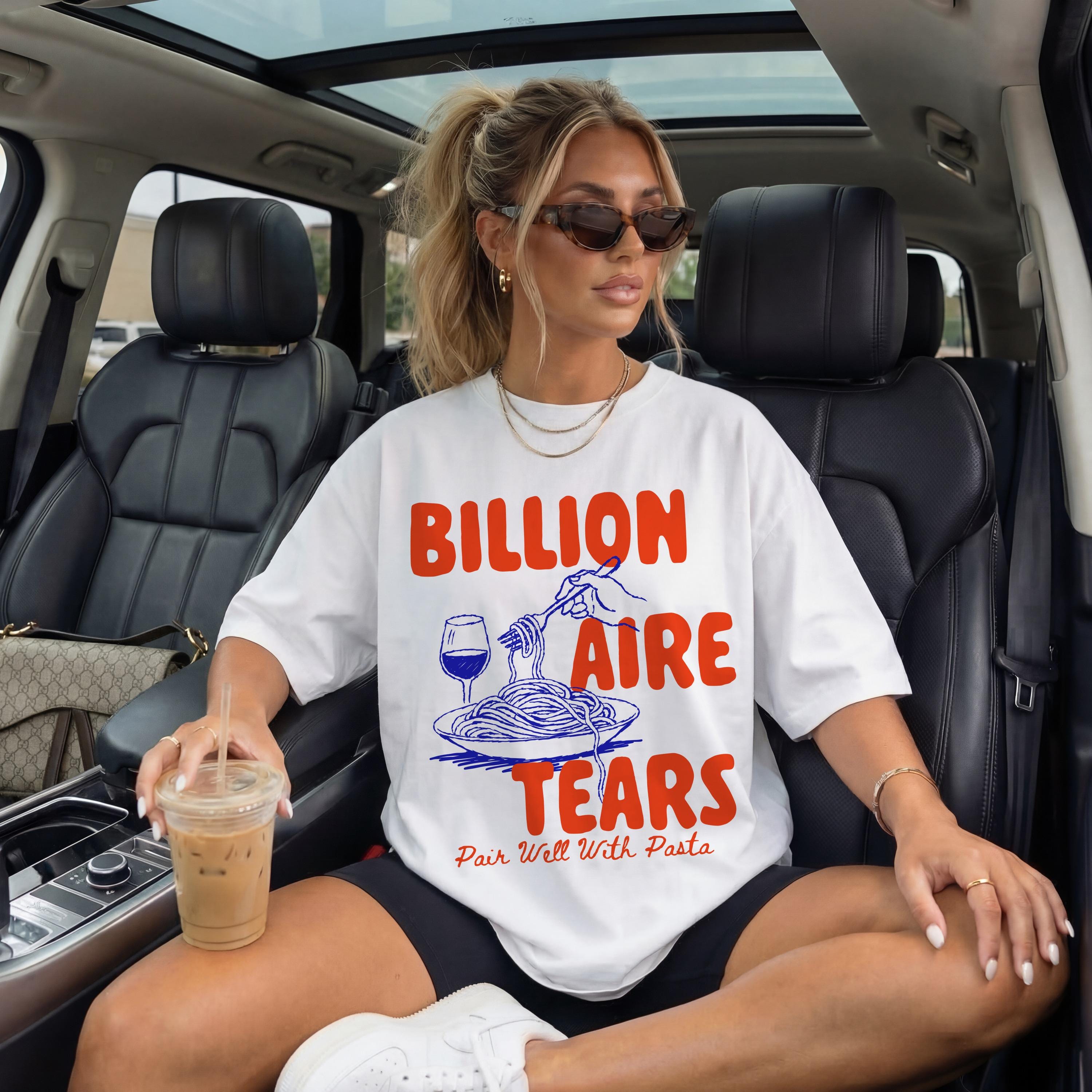 Woman in white t-shirt with &amp;quot;Billionaire Tears Pair Well With Pasta&amp;quot; graphic, sitting in a car.