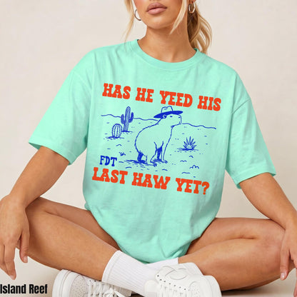 Mint green t-shirt with a desert scene and capybara graphic, reading &amp;quot;HAS HE YEED HIS FDT LAST HAW YET?&amp;quot;.