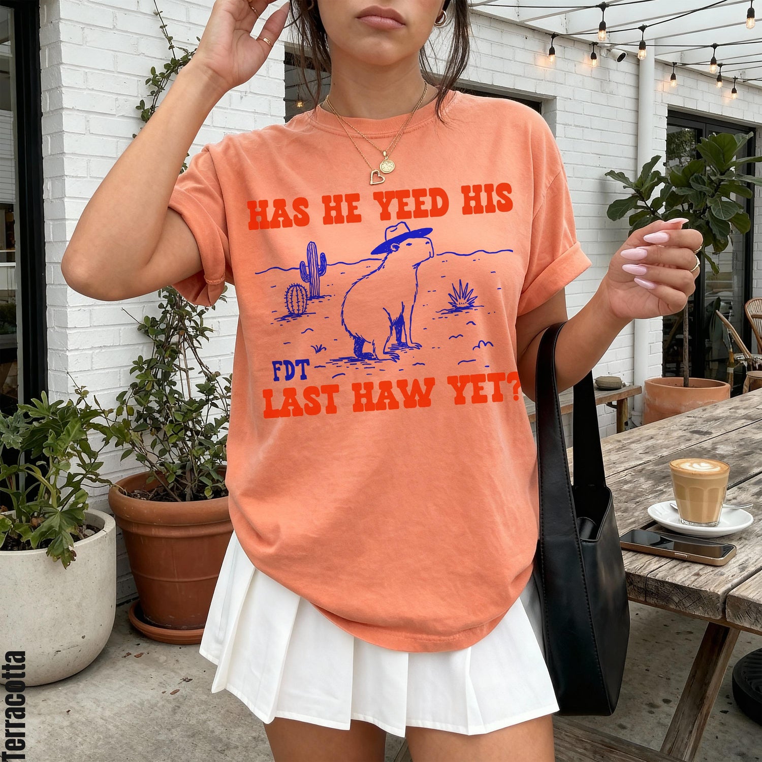 Orange t-shirt with distressed graphic of capybara in cowboy hat and text.