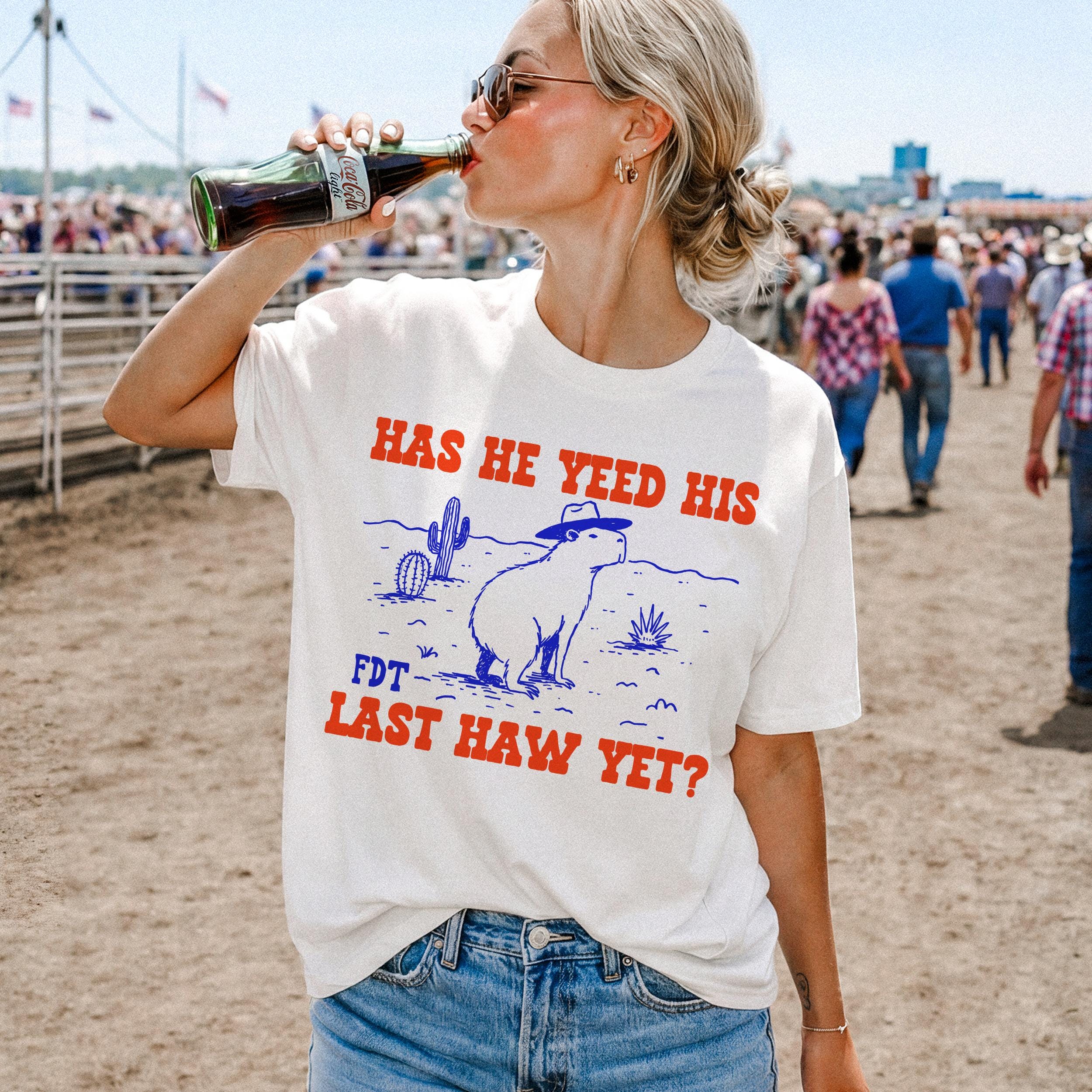 White t-shirt with graphic of capybara wearing hat and text: HAS HE YEED HIS FDT LAST HAW YET?
