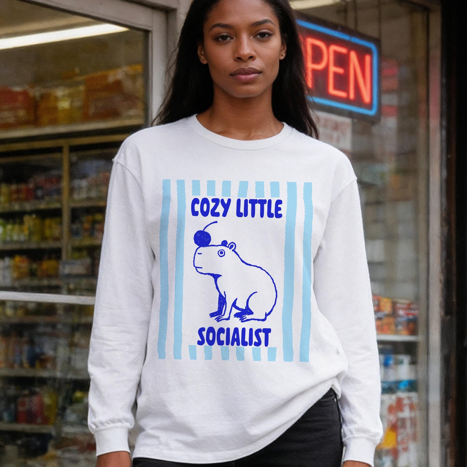 White long-sleeve shirt with blue capybara graphic and text &amp;quot;COZY LITTLE SOCIALIST&amp;quot;.
