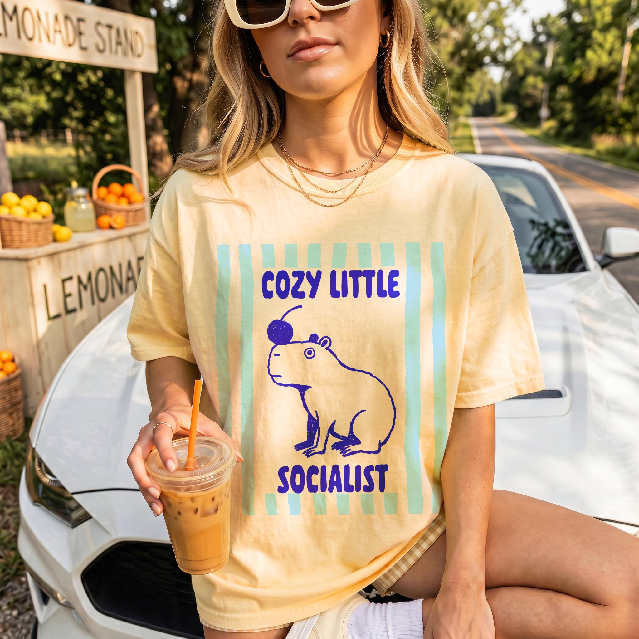 Yellow t-shirt with a capybara graphic and text &amp;quot;COZY LITTLE SOCIALIST&amp;quot;.