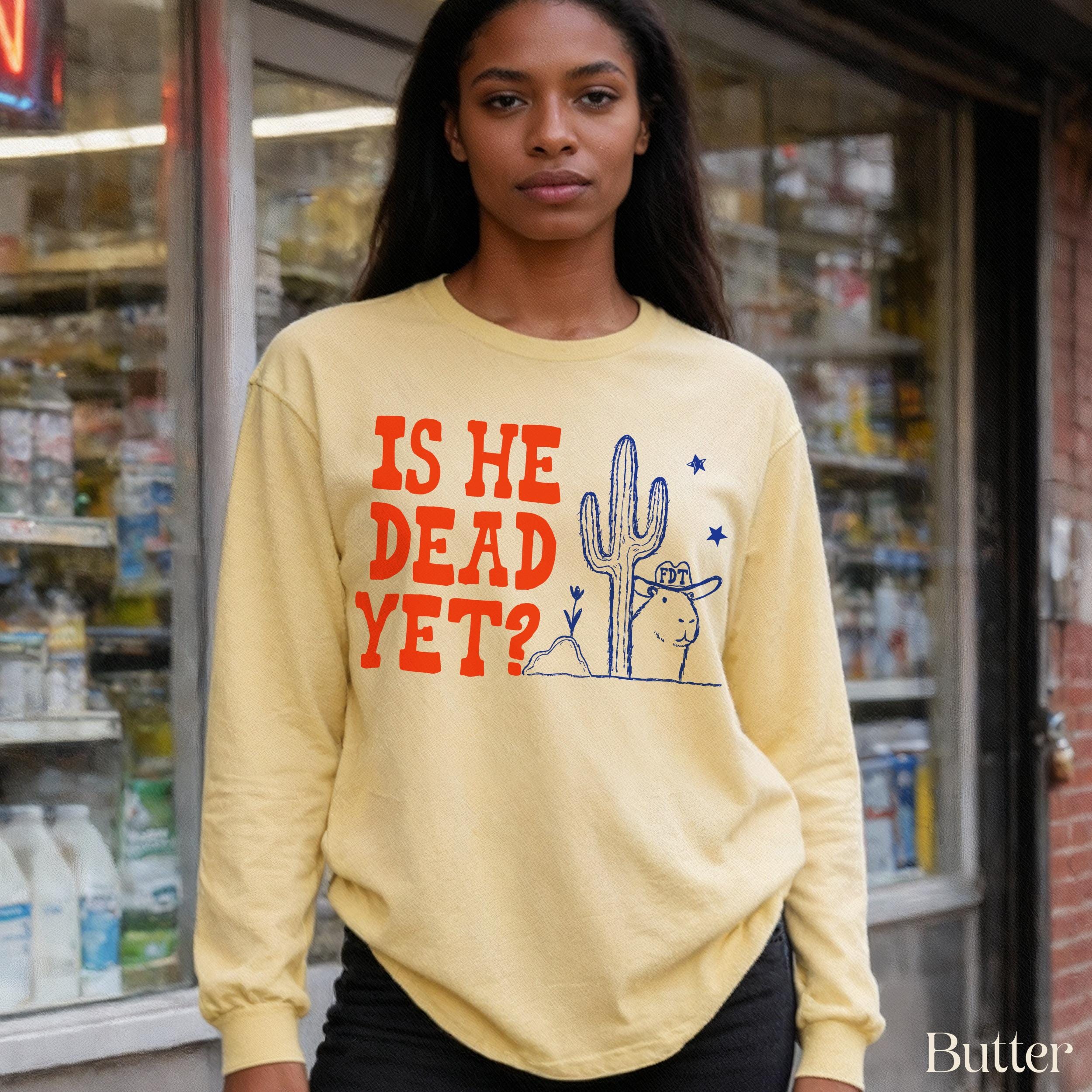 Yellow long sleeve shirt with orange &amp;quot;IS HE DEAD YET?&amp;quot; text and desert graphic.