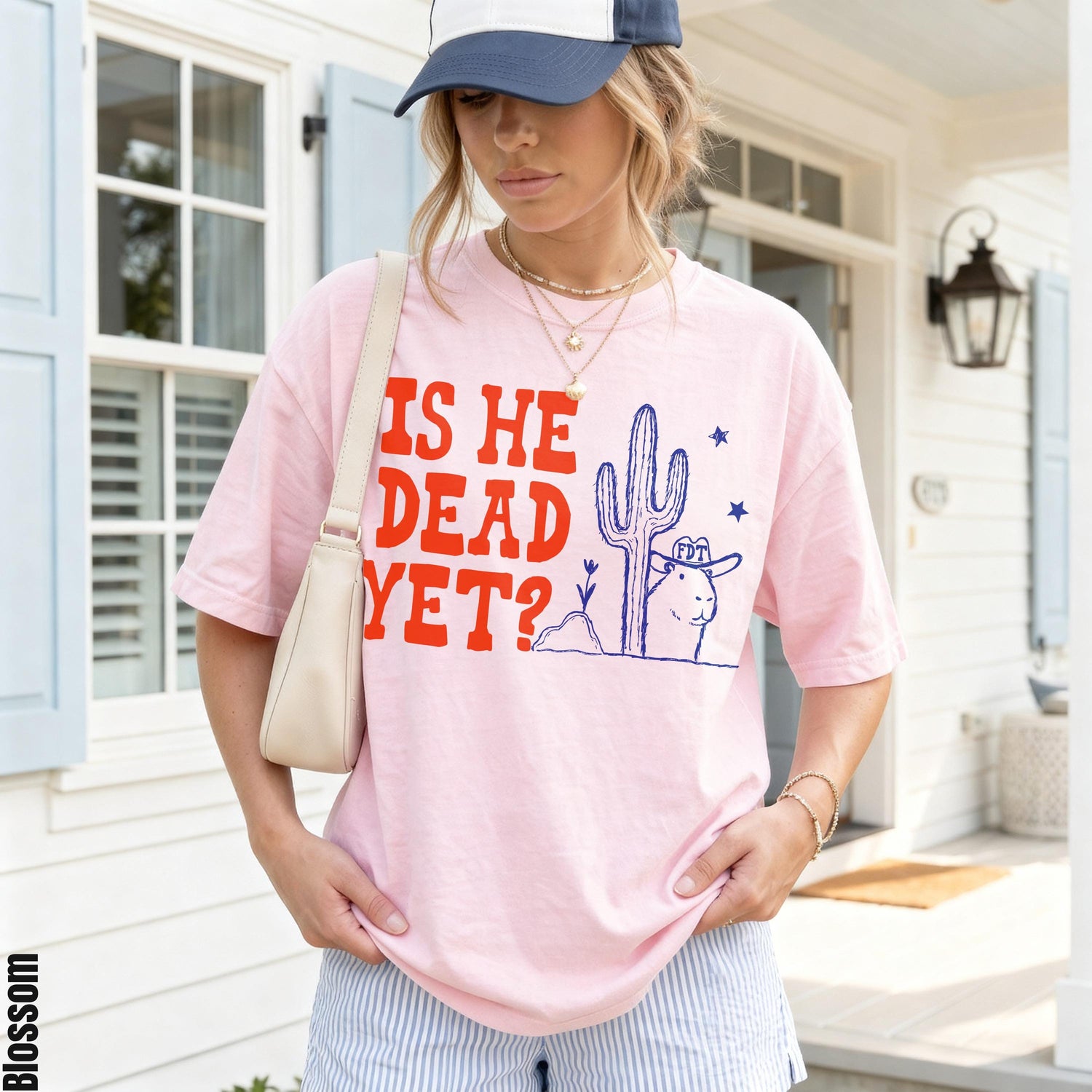 Pink t-shirt with text &amp;quot;IS HE DEAD YET?&amp;quot; and cartoon desert scene.