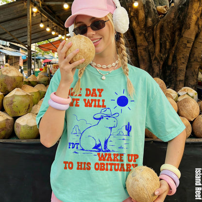 Mint t-shirt with a capybara in a cowboy hat and desert graphic, text reads &amp;quot;one day we will wake up to his obituary&amp;quot;.